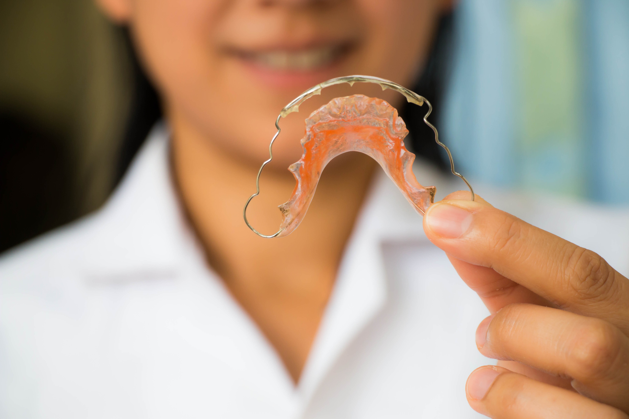 Orthodontic assistant at Goff Orthodontics holding a metal removable retainer